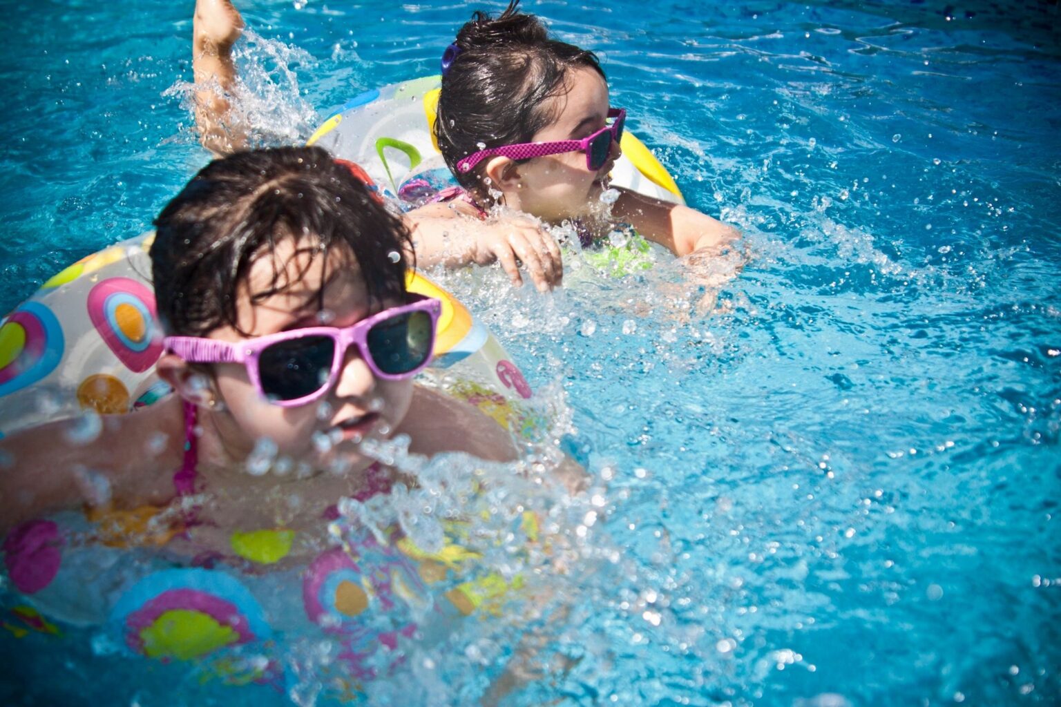 Little girls with sunglasses on in swimming pool