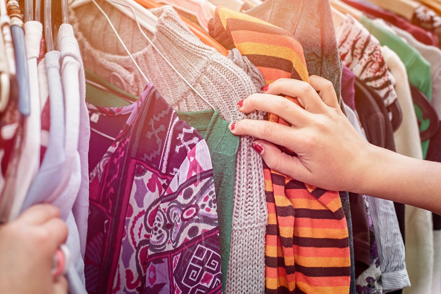 woman looking through dresses hanging on hangers